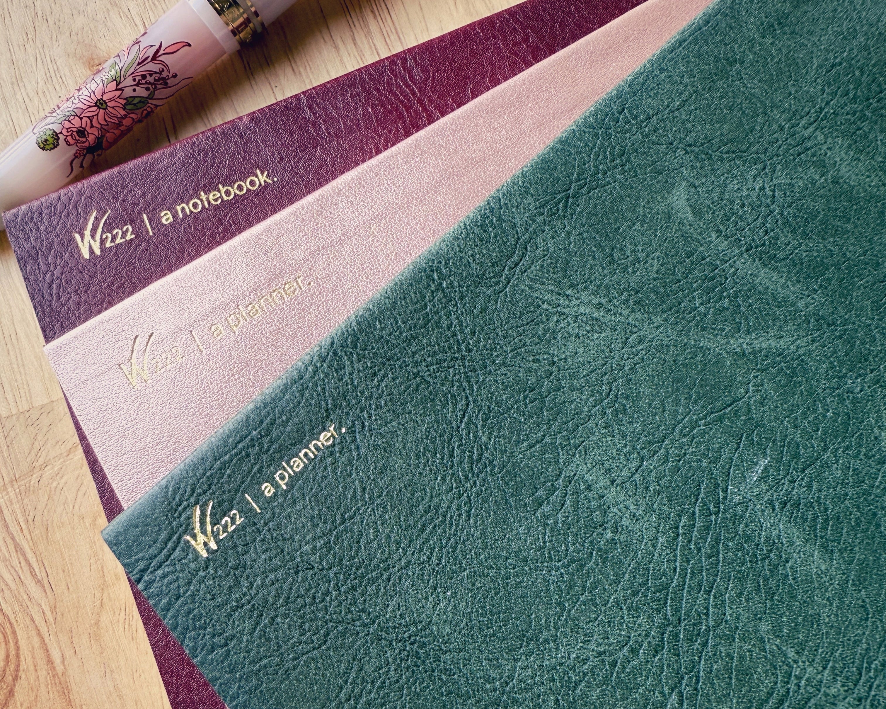2026 Wonderland 222 planners and notebook.  Alpenglow, North Slope and Lingonberry colors next to a Sailor Pro Gear slim Ancora fountain pen in Vintage Boquet