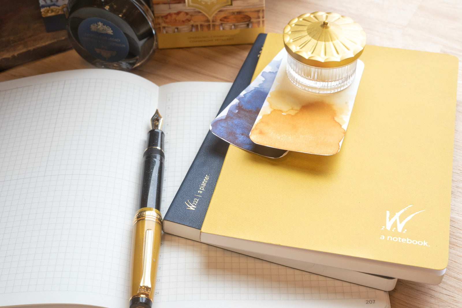 Wonderland 222 Planner and Notebook open on top of open notebook on desk with fountain pen and ferris wheel press ink