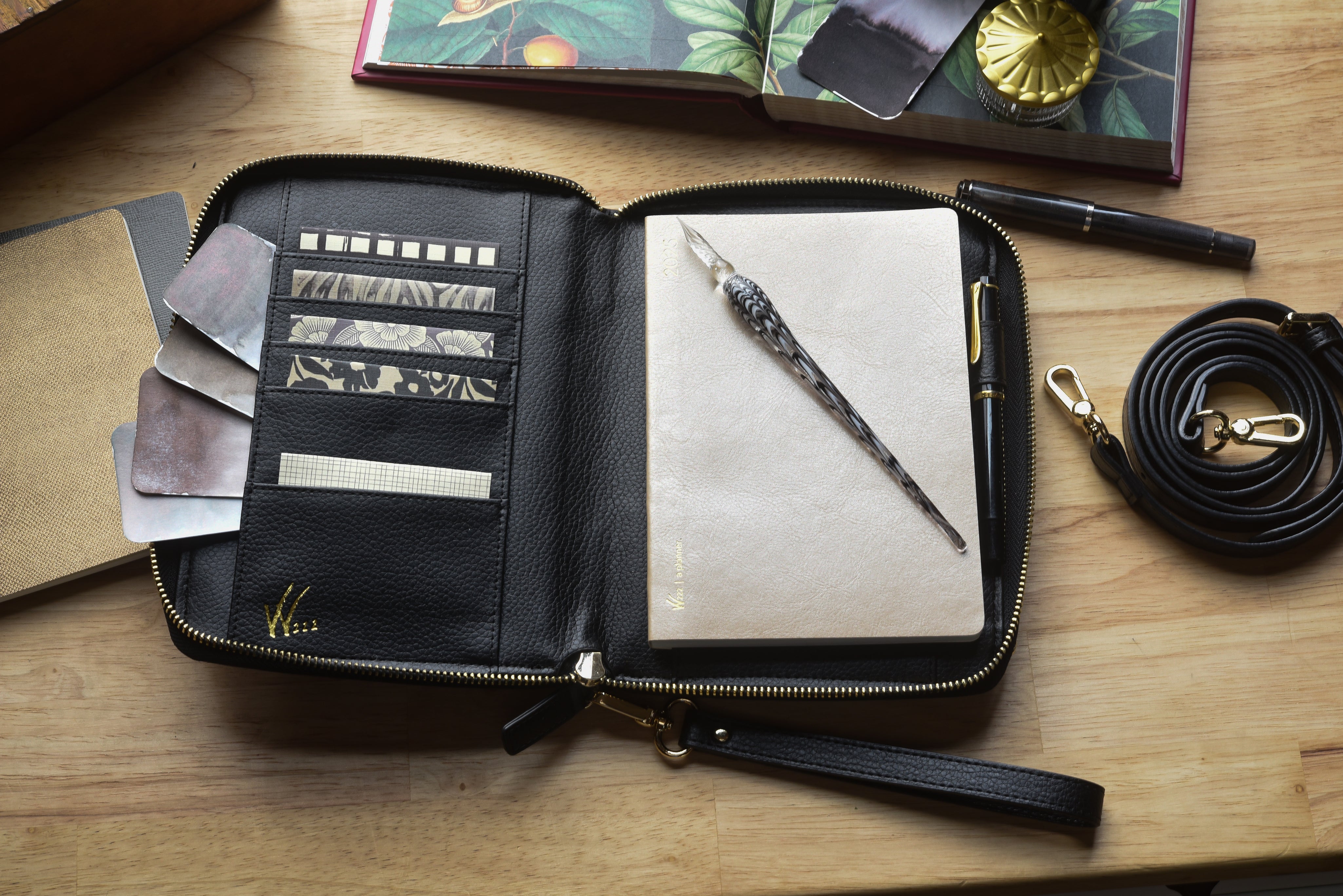 Wonderland 222 black planner purse styled with fountain pens, glass dip pen, patterned washi tape, and a minimalist notebook for thoughtful everyday planning