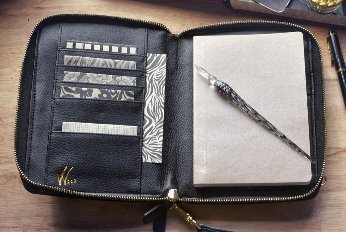 Wonderland 222's planner purse cover open with planner inside sitting on top of a desk.